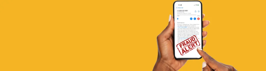 A hand with a cell phone in it. The screen says Fraud Alert